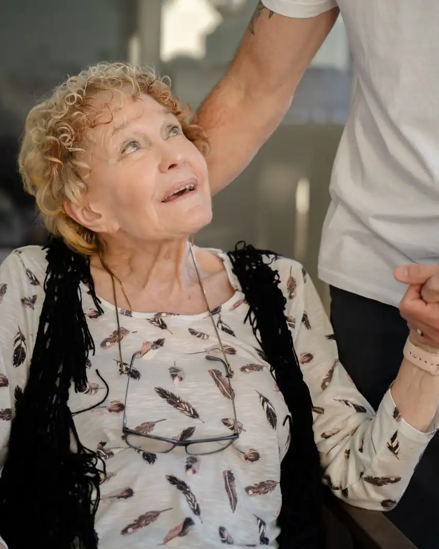 A support worker holding the hand of an older person indoors