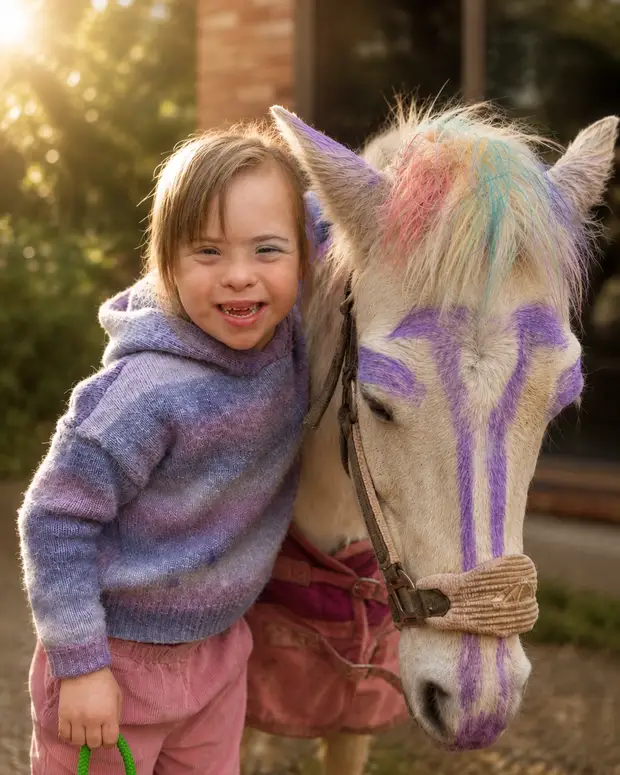 A child in a purple jumper proudly showing a painted wooden pony